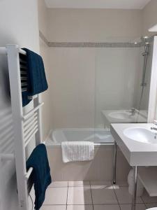 een witte badkamer met een wastafel, een bad en een douche bij Appartement avec Sauna et Piscine au bord de mer in Plougonvelin
