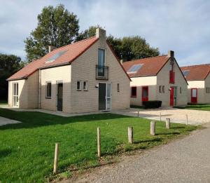 una casa con techo rojo en un patio verde en Vakantiehuis 6pers op park 't Broeckhuys in Ewijk groot Zwemplas in het land van Maas & Waal niet voor arbeidsmigranten, en Ewijk