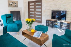 Apartament z historią, Klahra MyWeek في لوندك زدرووي: غرفة معيشة مع كراسي زرقاء و إناء من الزهور على طاولة