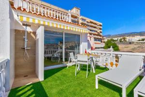 a balcony with white chairs and a table on the grass at Sea sand and sun in Callao Salvaje