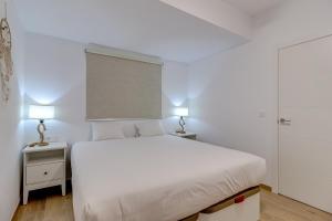a white bedroom with a white bed and two lamps at Sea sand and sun in Callao Salvaje +17 photos