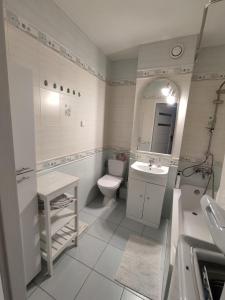 a white bathroom with a toilet and a sink at Gallery Apartament in Warsaw
