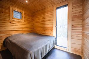 a bedroom with a bed in a wooden room with a window at Black Work Levi Aihki in Kittilä