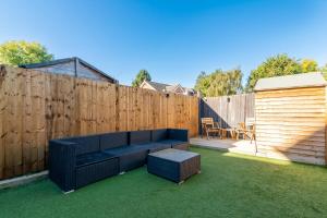 a backyard with a blue couch and a wooden fence at GuestReady - Moonbeam Cottage Quiet village in Eltham