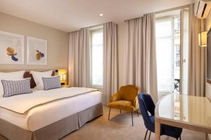 パリにあるホテル デュミニー バンドームのベッド、テーブル、椅子が備わるホテルルームです。