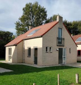 una gran casa de ladrillo con techo rojo en Vakantiehuis 6pers op park 't Broeckhuys in Ewijk groot Zwemplas in het land van Maas & Waal niet voor arbeidsmigranten, en Ewijk