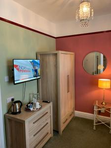 a room with a tv and a cabinet and a mirror at Glendower House in Minehead