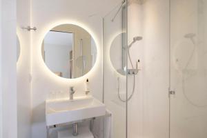 a white bathroom with a sink and a mirror at Hotel Duminy-Vendome in Paris