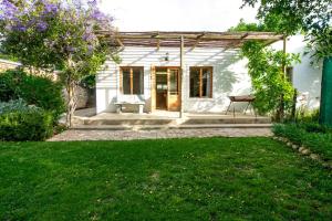 a white house with a bench in a yard at Garden Cottage in Graaff-Reinet