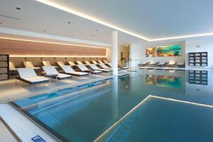 - une piscine avec des chaises et des tables dans un bâtiment dans l'établissement Spa Hotel Bründl, à Bad Leonfelden