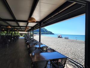 a restaurant on the beach with tables and chairs at Hotel Neptun Kvariati in Kvariati