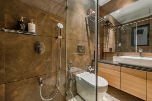 a bathroom with a shower and a toilet and a sink at SaffronStays Nishta - 4BR pet-friendly villa with pool, turf, gazebo & terrace BBQ views in Alibaug in Alibaug +14 photos