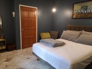 a bedroom with a white bed with a yellow chair at REQUELstore in Sungai Pelik