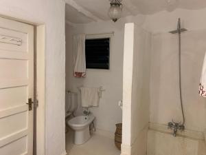 La salle de bains blanche est pourvue de toilettes et d'une fenêtre. dans l'établissement Kaleb's Serviced Beachfront Villa, à Malindi