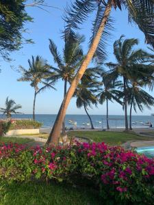 馬林迪的住宿－Kaleb's Beachfront Villa，享有海滩、棕榈树和鲜花的景致。