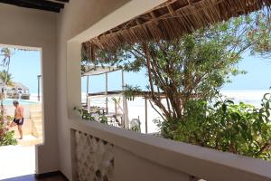 a room with a view of the beach from a balcony at Red Monkey Beach Lodge in Jambiani