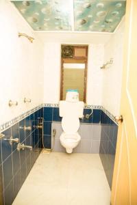 uma casa de banho com WC e azulejos azuis e brancos em Srujan Sarai Service Apartment em Mumbai
