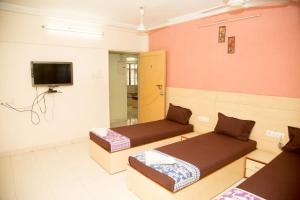 a room with two beds and a flat screen tv at Srujan Sarai Service Apartment in Mumbai