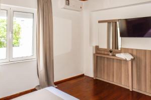 a hotel room with a bed and a flat screen tv at La Maison Plakes Rooftop Apt in Skiathos