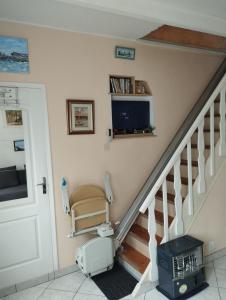 a room with a staircase with a chair and a tv at chambre d'hote dans maison individuelle in Saint Malo