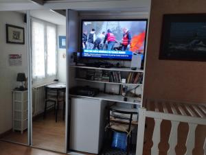 a living room with a tv and a entertainment center at chambre d'hote dans maison individuelle in Saint Malo