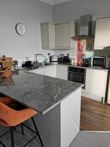 cocina con armarios blancos y encimera en Upmarket 2 bedroom apartment with sea views, en Torquay