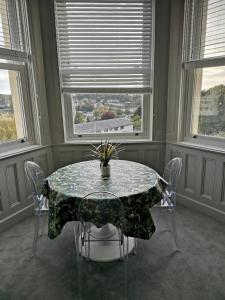 a dining room with a table and two windows at Upmarket 2 bedroom apartment with sea views in Torquay