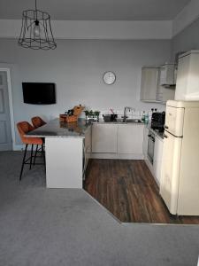 a kitchen with a white refrigerator and a table at Upmarket 2 bedroom apartment with sea views in Torquay