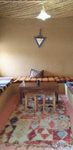 Cette chambre comprend un canapé, une table et un tapis. dans l'établissement Auberge Camping La Khaima, à Merzouga