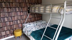ein Etagenbett und ein Stuhl in einem Zimmer mit Büchern in der Unterkunft Lovely apartment @ the Old barn. in Kircubbin