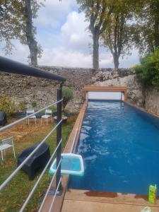 una piscina en un patio con sillas y una pared en Gîte de la Mignonerie du Château de Jallanges pour 19 personnes avec 4 ou 7 chambres, en Vernou-sur-Brenne