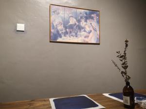 a painting on a wall with a bottle on a table at REQUELstore in Sungai Pelik