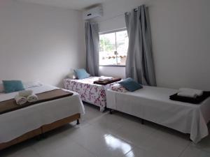 - 2 lits dans une chambre avec fenêtre dans l'établissement Hospedagem Casa Branca Localizada em um bairro nobre de Capitólio, Escarpas do Lago, à Capitólio
