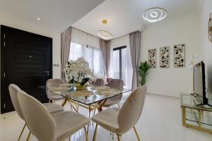 ein Esszimmer mit einem Glastisch und Stühlen in der Unterkunft Primestay - Damac Hills 2 Aster Villa 3 Bedroom in Dubai