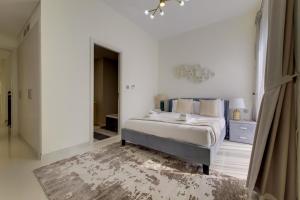 ein weißes Schlafzimmer mit einem Bett und einem Spiegel in der Unterkunft Primestay - Damac Hills 2 Aster Villa 3 Bedroom in Dubai