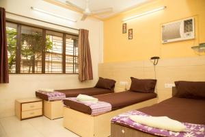 a room with two beds and a window at Srujan Sarai Service Apartment in Mumbai