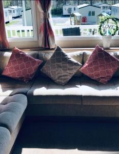 a couch with four pillows on it in front of a window at Tummel valley holiday park in Tummel Bridge