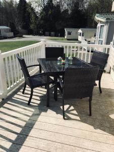 a table and chairs on a deck with a fence at Tummel valley holiday park in Tummel Bridge