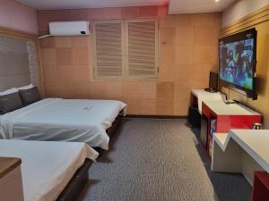 a hotel room with two beds and a flat screen tv at Sharp Hotel Jeonju in Jeonju