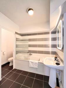 uma casa de banho branca com uma banheira e um lavatório em Hôtel du Commerce em Cluny