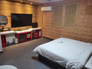a bedroom with a bed and a flat screen tv at Sharp Hotel Jeonju in Jeonju