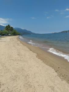 una playa de arena con palmeras y el océano en Studio Tipo Chale PRAIA SANTA TEREZA, en Ilhabela