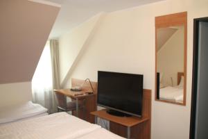 Schlafzimmer mit einem Bett und einem Flachbild-TV in der Unterkunft Hotel Stadt Kamen in Kamen