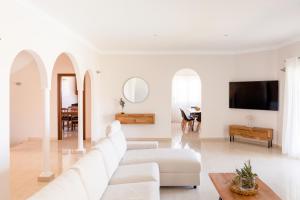 a white living room with white furniture and a flat screen tv at Modern Villa with heated pool and mountain views in Arona