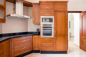a kitchen with wooden cabinets and a microwave at Modern Villa with heated pool and mountain views in Arona