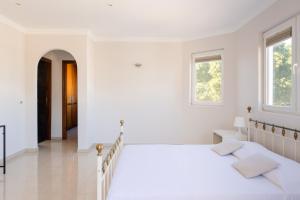a white bedroom with two beds and two windows at Modern Villa with heated pool and mountain views in Arona
