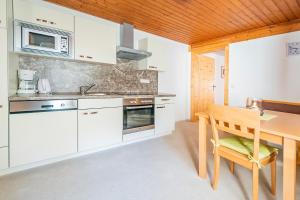 a kitchen with white cabinets and a wooden table at Stallhäusl in Schladming