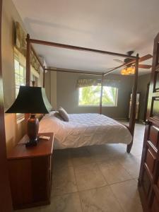 ein Schlafzimmer mit einem Himmelbett und einem Tisch mit einer Lampe in der Unterkunft Los Porticos in Placencia Village