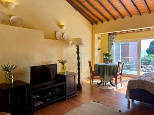 a bedroom with a table and a television and a dining room at Casa O Refúgio in Lagoa