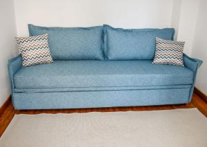a blue couch with two pillows in a room at La Maison Plakes 3 BDR Apt in Skiathos